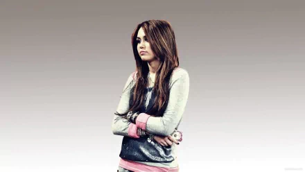 A high-definition desktop wallpaper featuring Miley Cyrus, with her arms crossed and a contemplative expression, set against a gradient background.