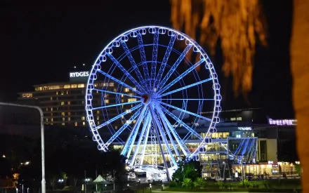 The Wheel of Brisbane illuminated at night, showcasing a vibrant display of lights against the backdrop of Brisbane's skyline in Queensland, Australia. A stunning man-made attraction.