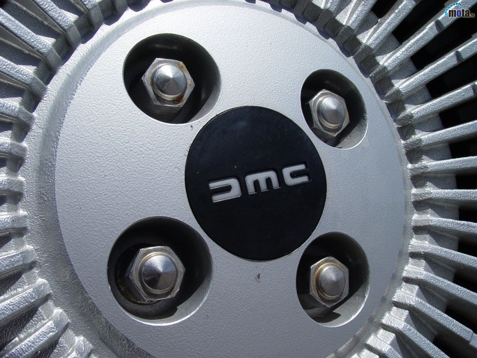 HD PC desktop wallpaper showing a close-up of a DeLorean vehicle wheel hub with DMC center cap and exposed lug nuts.
