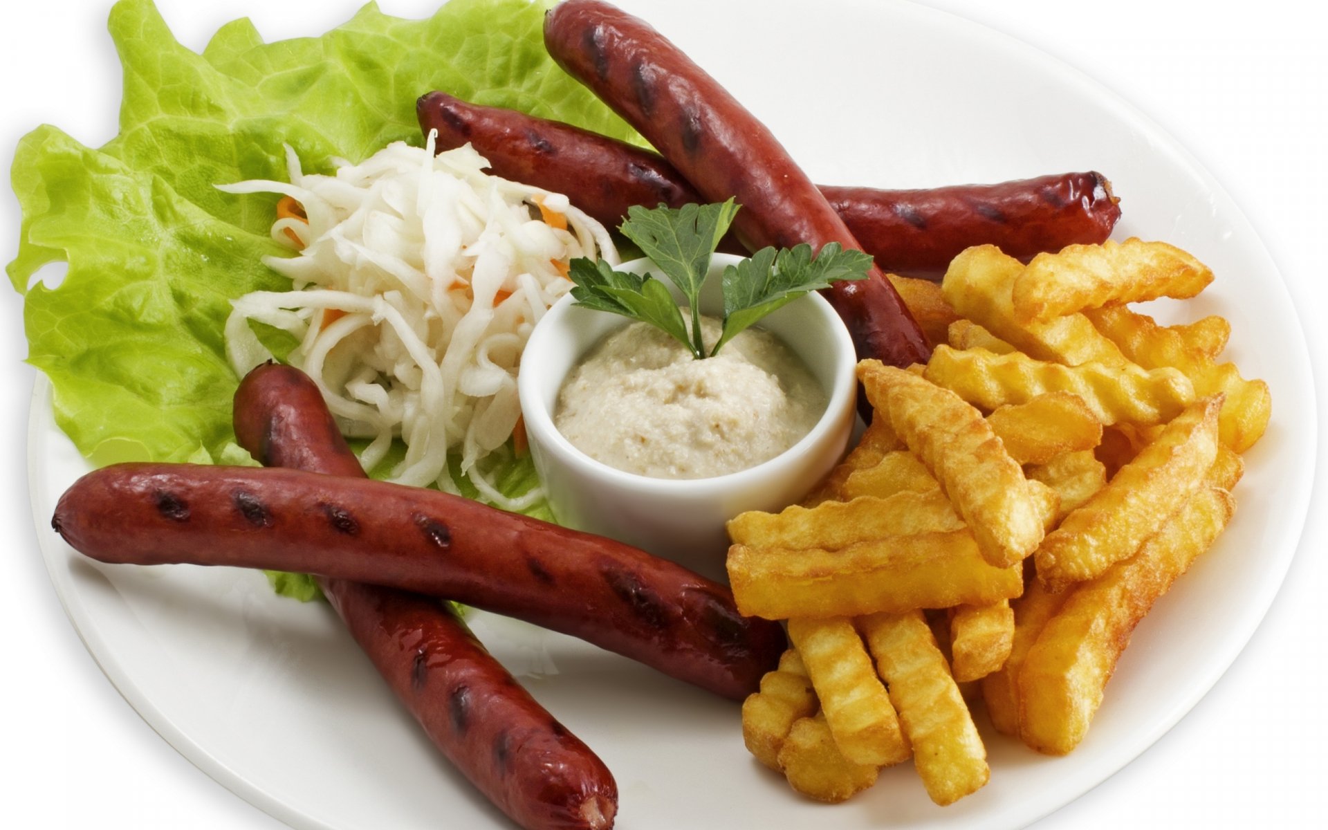HD PC desktop wallpaper featuring a meal with grilled sausages, crinkle-cut fries, lettuce, shredded salad, and a small bowl of dipping sauce on a white plate.
