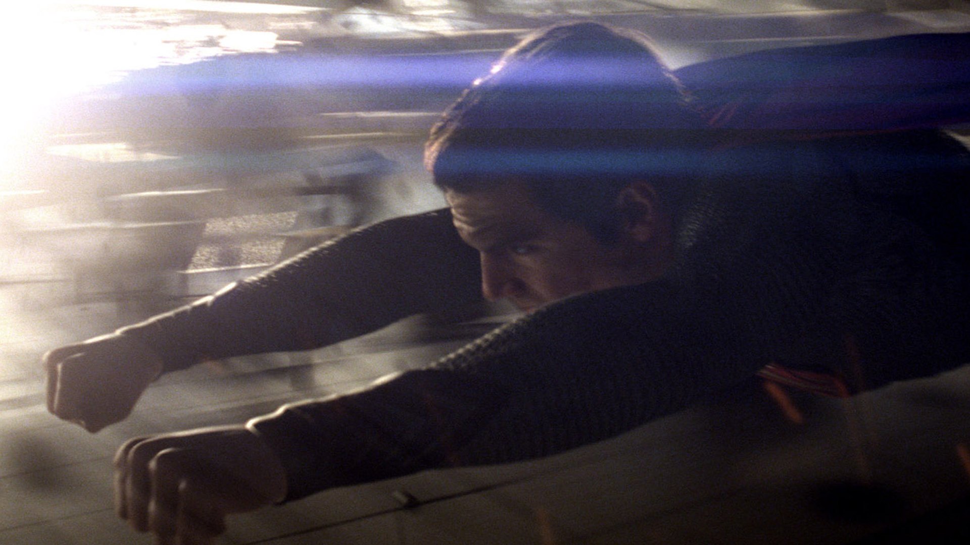 HD PC desktop wallpaper from the movie Man of Steel: a dark‑suited superhero flying in motion, blurred city below and streaks of light across the frame.