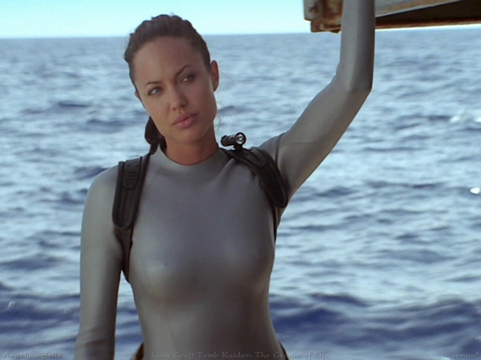 Lara Croft: Tomb Raider movie 2K Quad HD PC desktop wallpaper and background — Lara Croft in a silver wetsuit with a backpack, standing at sea.
