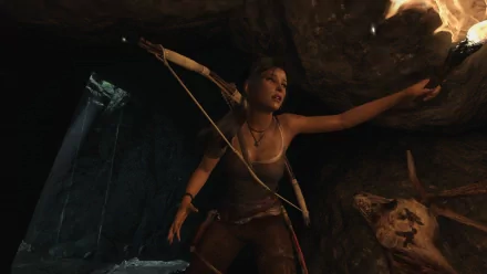 HD PC desktop wallpaper featuring Lara Croft from the video game Tomb Raider, poised with a bow in a dark, cave-like environment illuminated by torchlight.