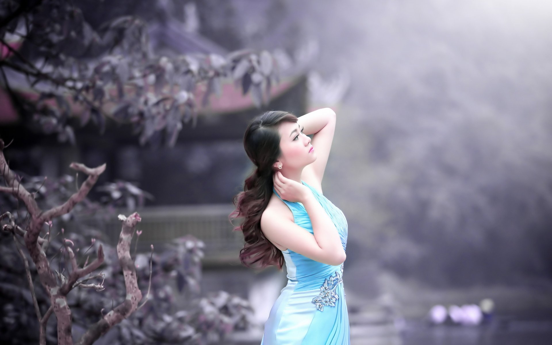 HD desktop wallpaper featuring an Asian woman in a blue dress, serenely posing in a misty, floral setting.