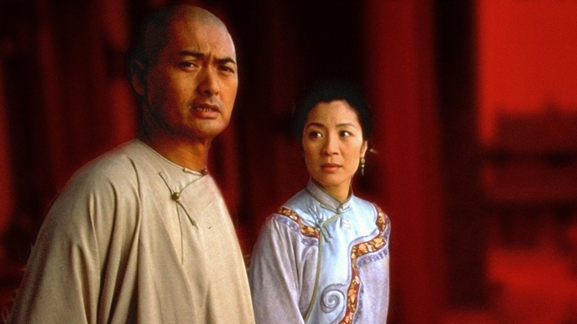HD desktop wallpaper from the movie Crouching Tiger, Hidden Dragon: two period-costumed characters in a contemplative pose against a red architectural backdrop.