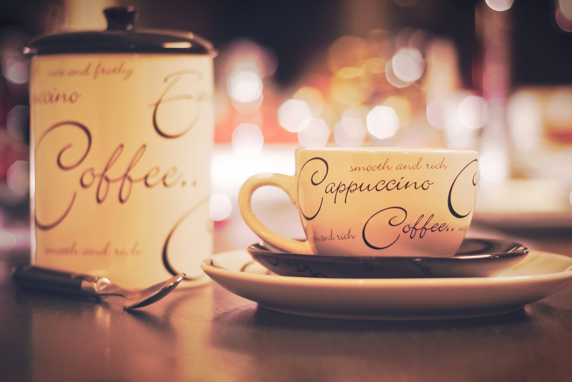 HD desktop wallpaper featuring a coffee cup and a candle with elegant script, set against a warm bokeh background highlighting food and coffee ambiance.