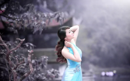 HD desktop wallpaper featuring an Asian woman in a blue dress, serenely posing in a misty, floral setting.