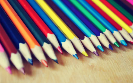A vibrant arrangement of colored pencils on a wooden surface, captured in HD photography. This image serves as an engaging desktop wallpaper or background.