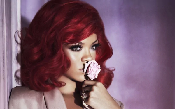 A striking HD wallpaper featuring Rihanna with red hair, holding a pink rose against a soft, purple background, embodying a blend of elegance and allure.