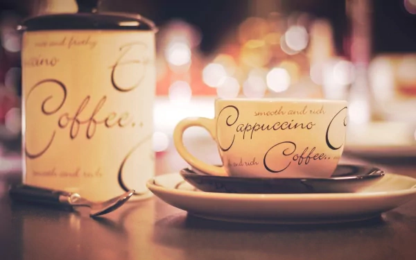 HD desktop wallpaper featuring a coffee cup and a candle with elegant script, set against a warm bokeh background highlighting food and coffee ambiance.