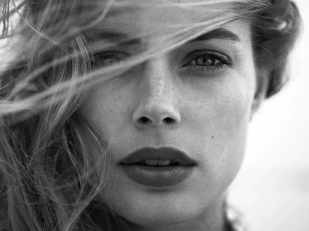 Black and white HD wallpaper featuring Doutzen Kroes with flowing hair, showcasing her striking features and captivating gaze.