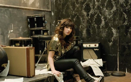 Demi Lovato sits in a stylish, music-themed setting, surrounded by instruments and sheets, captured in a high-definition desktop wallpaper.