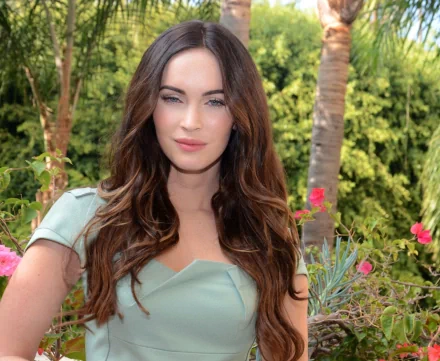 Megan Fox poses elegantly among lush greenery and vibrant flowers in this HD desktop wallpaper, capturing her striking beauty and charisma.