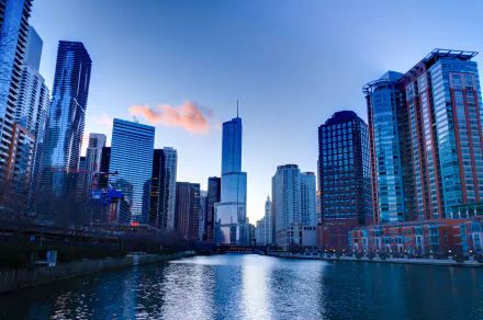 A stunning HD desktop wallpaper showcasing the Chicago skyline at dusk, with modern skyscrapers reflecting in the water. The scene captures the city's vibrant atmosphere and architectural beauty.
