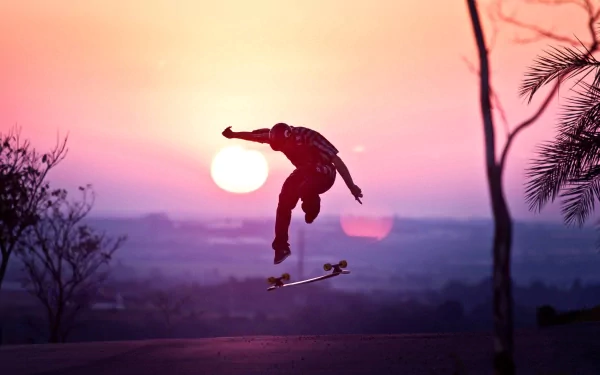 HD desktop wallpaper of a skateboarder performing a trick at sunset with a vibrant sky in the background.