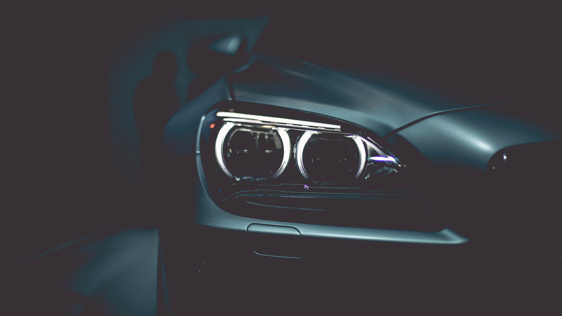 Close-up of a BMW vehicle headlight captured in a dark setting, presented as an HD PC desktop wallpaper and background.