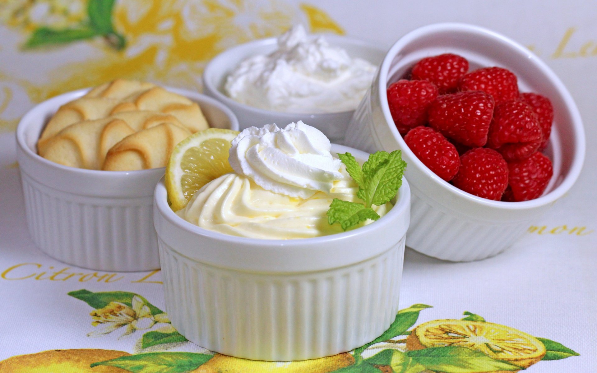 HD PC desktop wallpaper featuring close-up of three white ramekins filled with dessert elements: raspberries, whipped cream, and lemon mousse garnished with mint leaves.