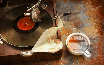 A vintage-inspired scene featuring a classic record player and a cup of coffee, evoking a nostalgic feel. This HD wallpaper adds a charming touch to any desktop background.