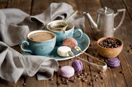 HD PC desktop wallpaper featuring a cozy coffee setup with a blue cup of coffee, macarons, a wooden bowl of coffee beans, and a metal coffee pot on a wooden table.