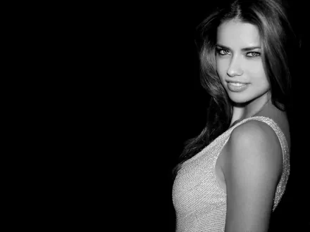 A striking black and white HD wallpaper featuring celebrity Adriana Lima, showcasing her captivating smile and glamorous pose against a dark background.