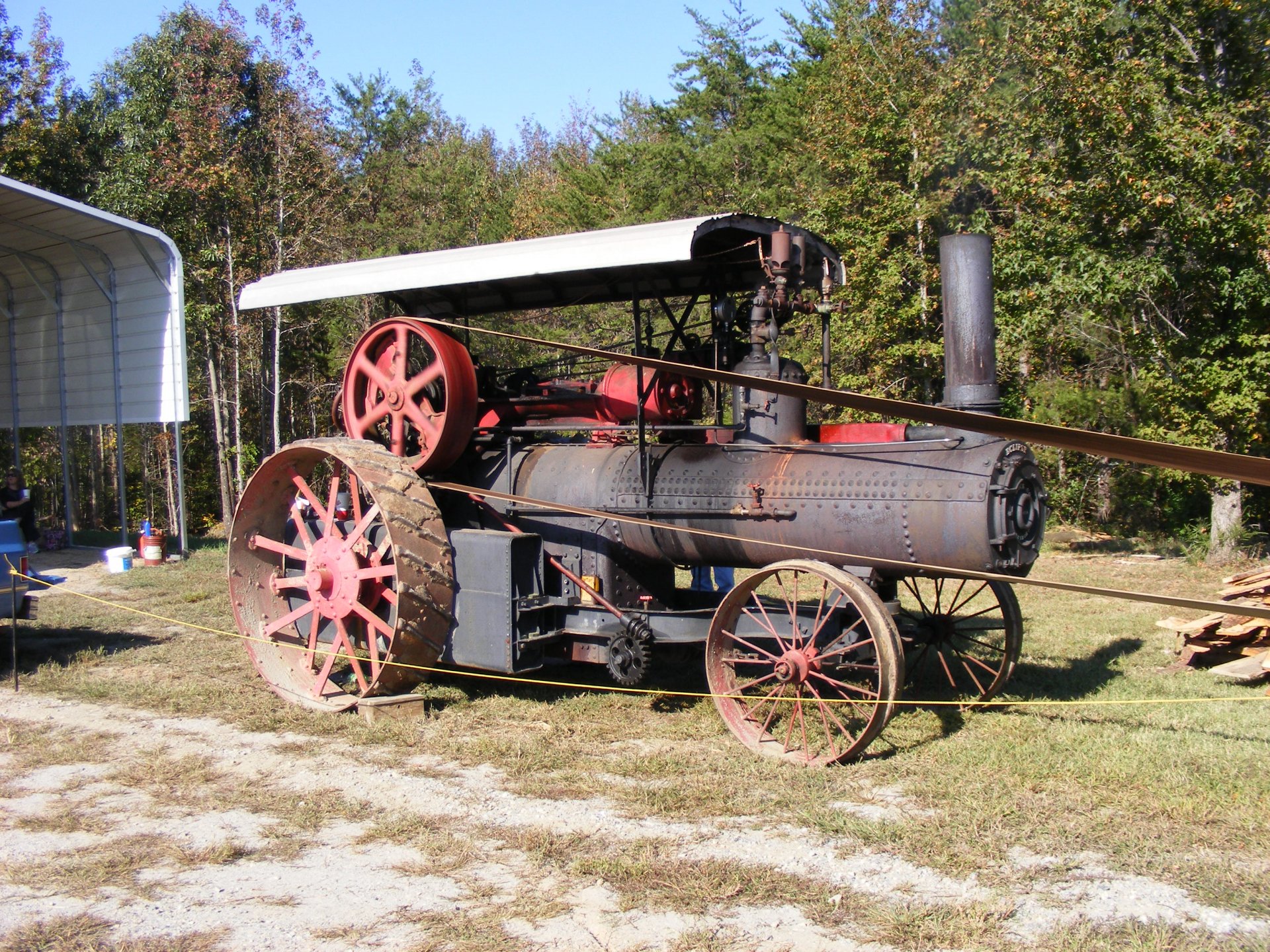 HD PC desktop wallpaper featuring a vintage tractor vehicle with large metal wheels set outdoors against a backdrop of trees and clear skies.