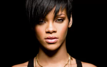 A striking HD desktop wallpaper featuring a close-up of Rihanna, showcasing her distinctive beauty and captivating gaze against a dark background, embodying the essence of music.