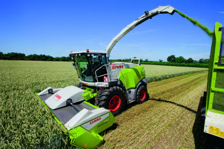 A Claas vehicle operates in a lush green field, harvesting crops under a clear blue sky. This stunning image serves as a vibrant 4K Ultra HD desktop wallpaper.