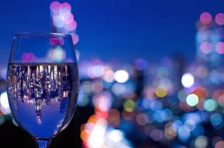 HD desktop wallpaper featuring a wine glass reflecting city lights against a vibrant bokeh background, blending food and wine themes with urban nightlife ambiance.