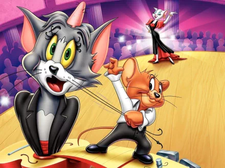 HD desktop wallpaper featuring Tom and Jerry from the TV show, with Tom looking surprised on stage and Jerry holding a rope, set against a vibrant background with spotlights and an audience.