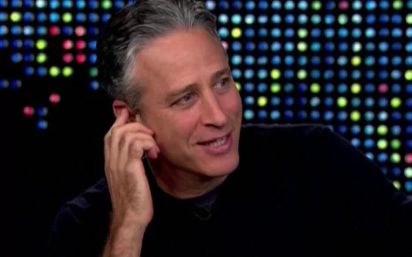 HD desktop wallpaper of a man from The Daily Show with Jon Stewart against a colorful lit background.