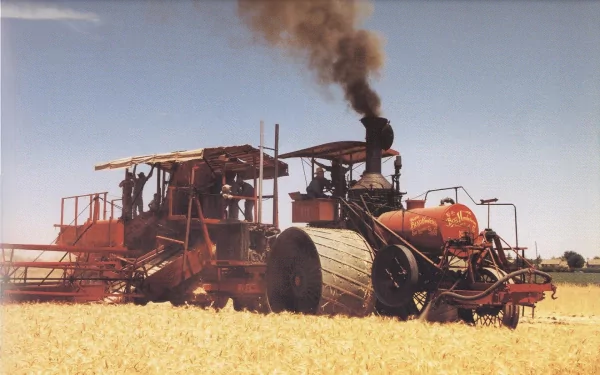 A vintage tractor works in a field, emitting smoke against a blue sky. This HD image serves as a striking desktop wallpaper and background for enthusiasts of agricultural machinery.