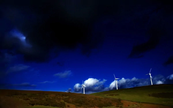HD desktop wallpaper showing a row of man-made wind turbines on a hill under a deep blue night sky with scattered clouds.