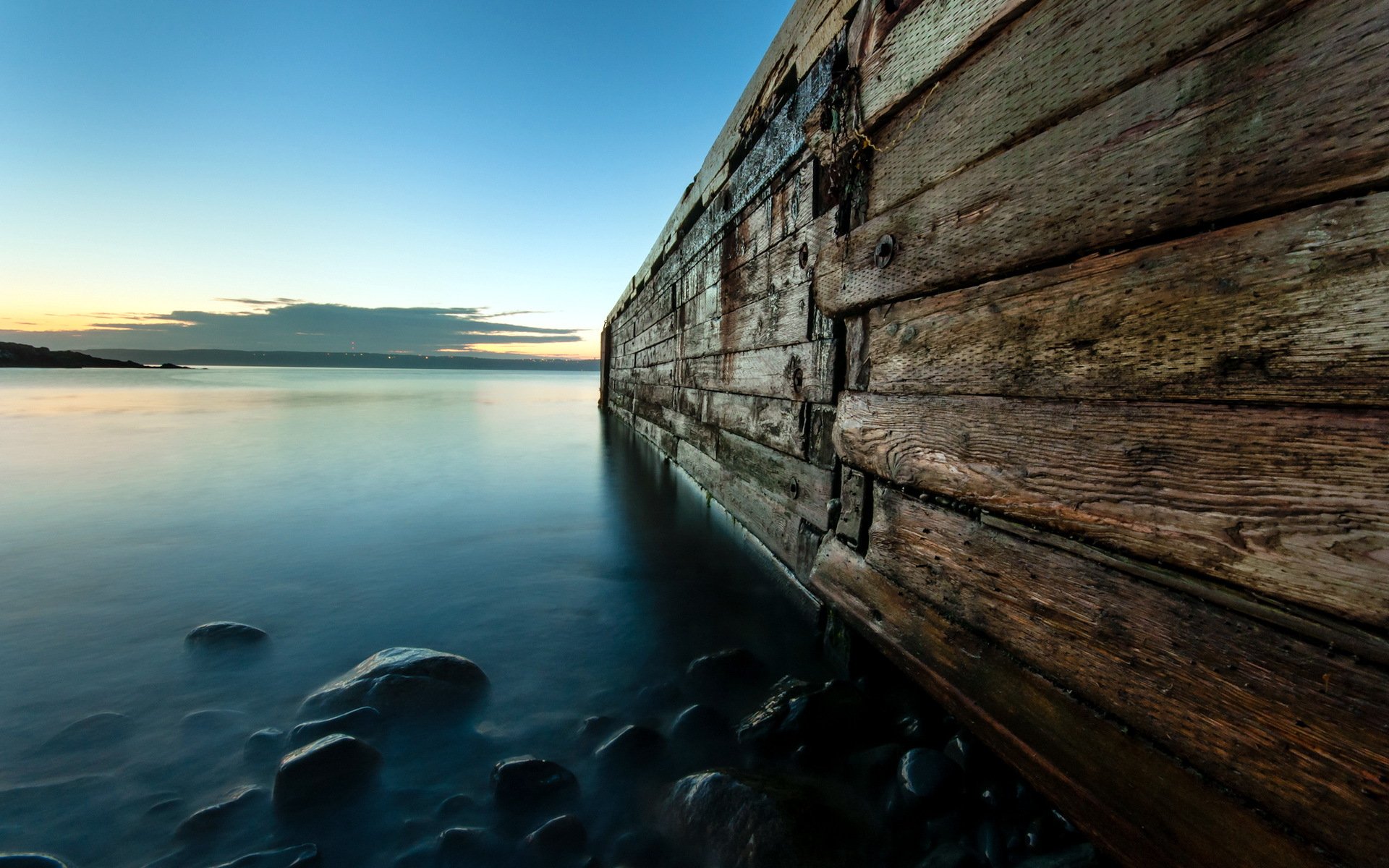 HD PC desktop wallpaper featuring a serene ocean scene at dusk with calm waters and a weathered wooden pier extending into the horizon.