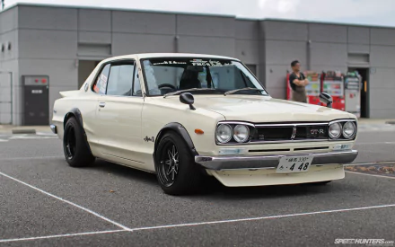 Classic Nissan vehicle — low-slung vintage coupe with black wheels parked in an urban lot, shown as an HD PC desktop wallpaper background.
