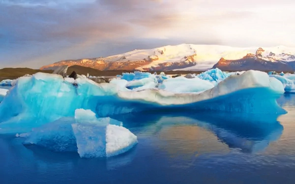 Nature glacier scene with vivid blue icebergs and snow-capped mountains at sunset — HD PC desktop wallpaper background.