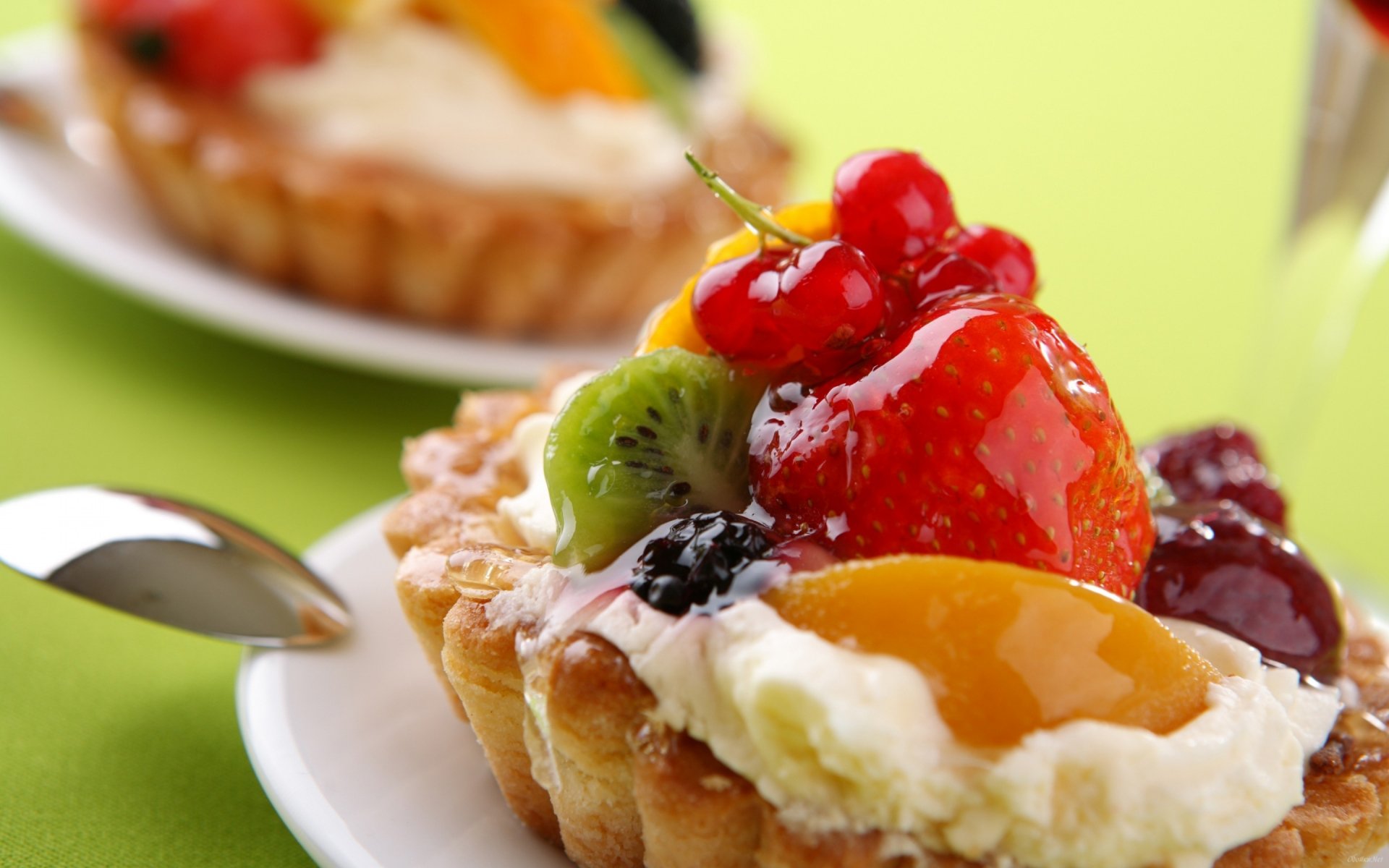 A vibrant, close-up image of delicious fruit tarts topped with cream and assorted fruits, set against a bright green background, making for an enticing HD PC desktop wallpaper.