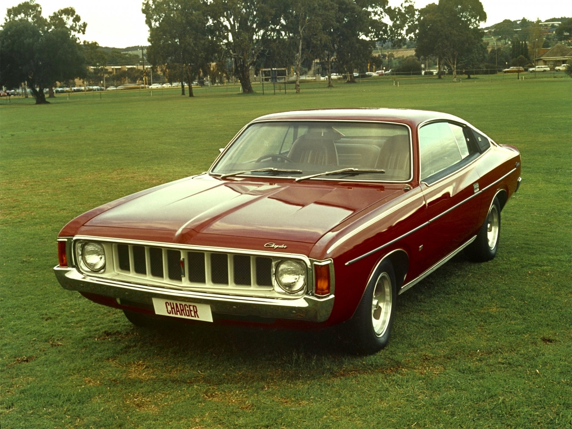 HD desktop wallpaper featuring a classic Chrysler Valiant Charger, a vintage Dodge Charger vehicle parked on a grassy field.