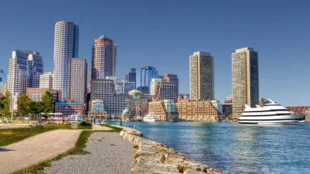 A vibrant HD desktop wallpaper featuring the skyline of Boston, showcasing modern buildings along the waterfront with a clear blue sky and serene waters.