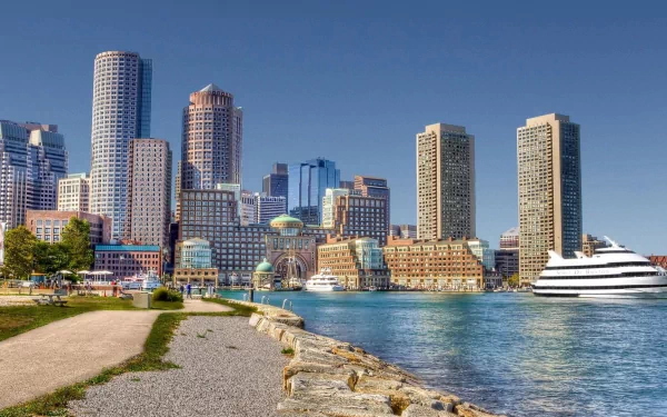 A vibrant HD desktop wallpaper featuring the skyline of Boston, showcasing modern buildings along the waterfront with a clear blue sky and serene waters.