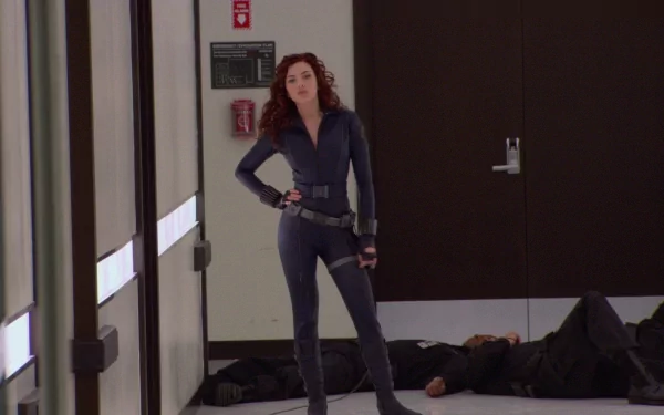 A scene from *Iron Man 2* featuring a confident female character in a sleek outfit, standing amid a dramatic backdrop with subdued lighting. An HD PC desktop wallpaper option.