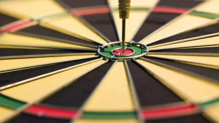 Close-up HD desktop wallpaper of a dart hitting the bullseye on a man-made dartboard, capturing precision and focus.
