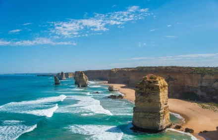 4K Ultra HD nature wallpaper showcasing a stunning coastline with towering rock formations, turquoise waves, and a clear blue sky.