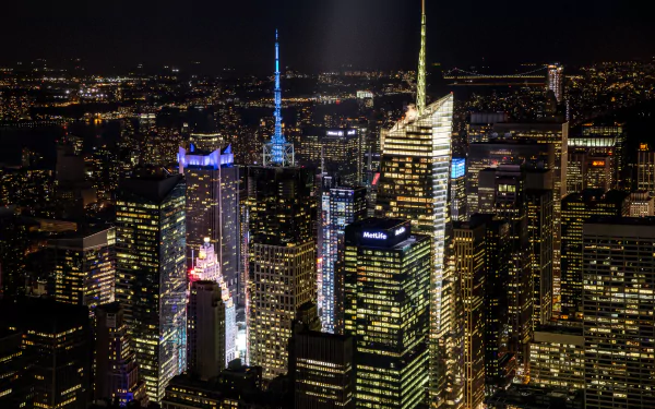 A stunning HD desktop wallpaper showcasing the vibrant skyline of Manhattan at night, highlighting iconic man-made structures illuminated against the dark sky.