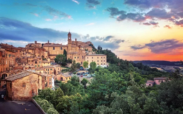 HD PC desktop wallpaper/background: panoramic view of man-made hilltop town Montepulciano at sunset, terracotta buildings clustered around a church tower above a green valley.