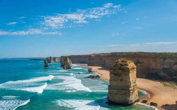 4K Ultra HD nature wallpaper showcasing a stunning coastline with towering rock formations, turquoise waves, and a clear blue sky.