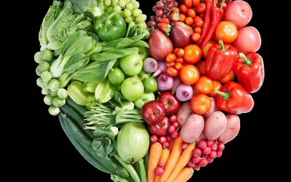 HD PC desktop wallpaper featuring a vibrant heart-shaped arrangement of fresh vegetables and fruits, showcasing green and red produce against a black background.