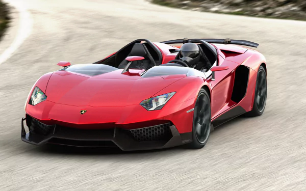 A red Lamborghini Aventador J sports car speeds along a curved road, captured in this HD PC desktop wallpaper and background.