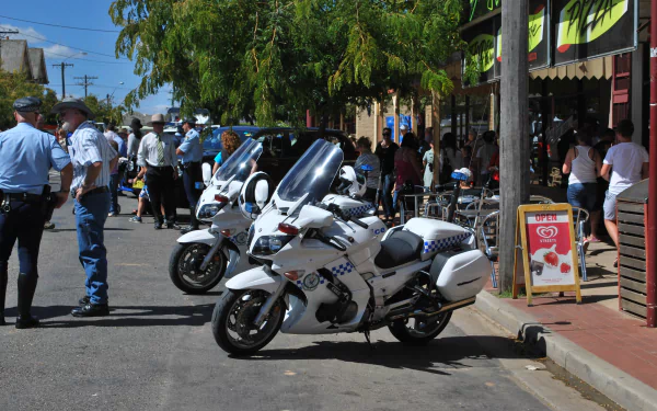 4K Ultra HD PC desktop wallpaper background of police vehicles — white police motorcycles parked on a sunny street with officers and a crowd nearby.