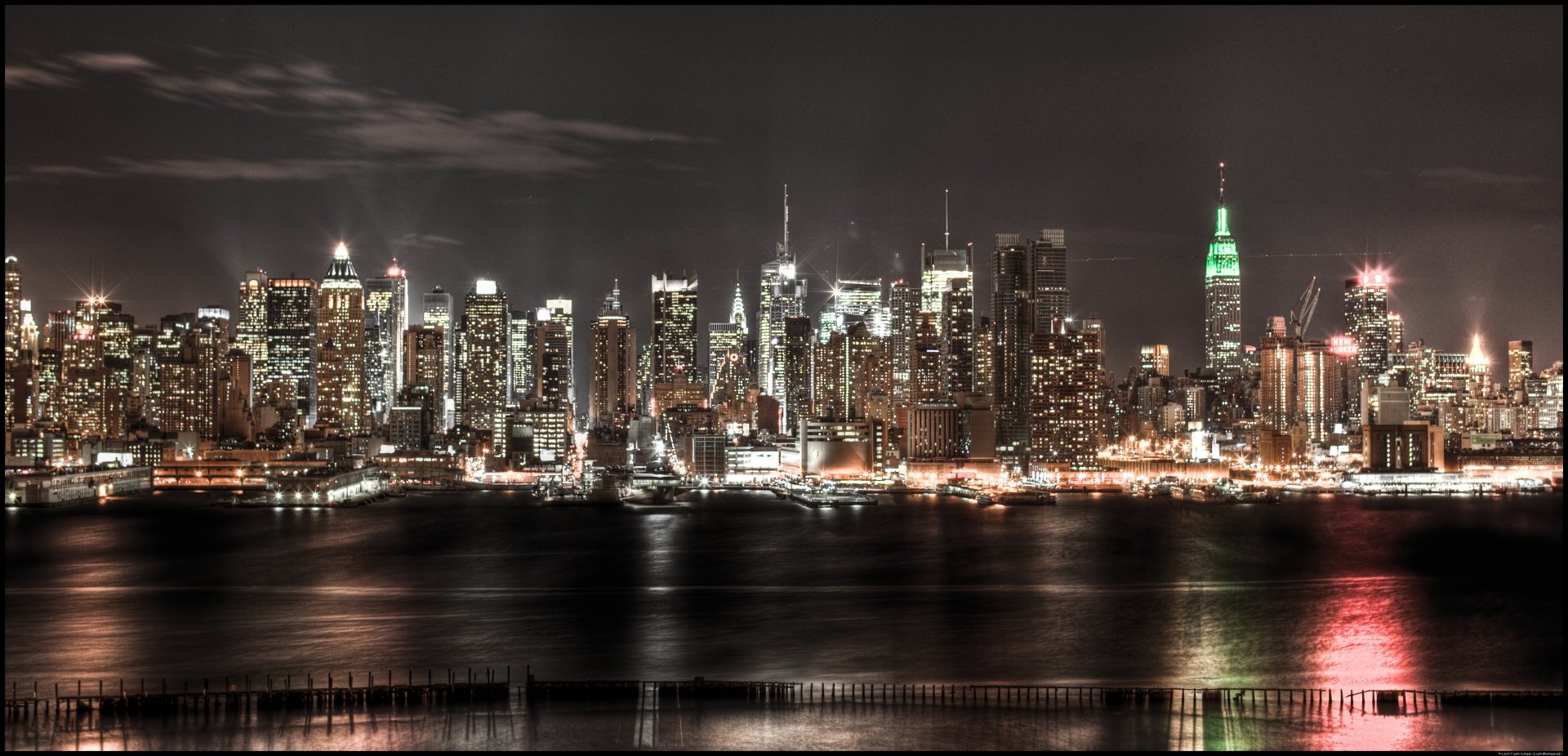 4K Ultra HD man-made skyline of New York City at night, featuring illuminated skyscrapers reflecting on the water.