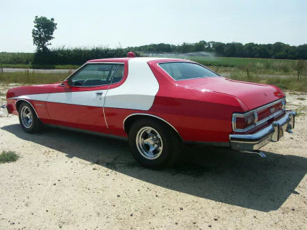 HD PC desktop wallpaper showing the Starsky & Hutch TV show's red Torino with white stripe parked on a gravel road, grassy fields and trees in the background.